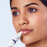 Woman applying a cosmetic product to her lips with a applicator.