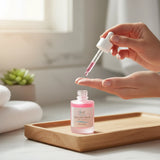 Elume Med Spa Lactic Acid Resurfacing Serum in a pink glass bottle with a dropper being applied to a hand
