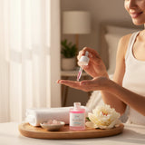 Elume Med Spa Lactic Acid Resurfacing Serum in a pink glass bottle with dropper, held by a woman in a bright room.