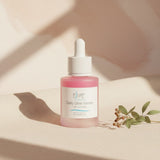 Elume Med Spa Lactic Acid Resurfacing Serum in a pink glass dropper bottle on a neutral background with dried leaves.