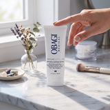 Elume Med Spa SUZANOBAGIMD Tinted Physical Defense SPF 50 mineral sunscreen tube on a marble vanity with a hand.